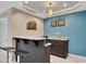 Basement bar area with granite countertop, stools, cabinets, and wall art at 11770 Ashwick Pl, Johns Creek, GA 30005