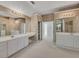 A large bathroom featuring dual sinks, a vanity, and lots of mirrors at 11770 Ashwick Pl, Johns Creek, GA 30005