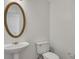 Simple powder room featuring a pedestal sink, oval mirror, and a toilet at 11770 Ashwick Pl, Johns Creek, GA 30005