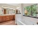 Charming bathroom with double sinks, a large soaking tub with a view, and wood cabinets at 718 Fincher Rd, Covington, GA 30016