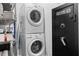 Compact laundry area featuring a stacked washer and dryer, accompanied by storage shelves and a secure safe at 1963 Main Nw St, Atlanta, GA 30318