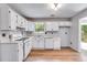 Bright kitchen with white appliances and cabinets, double bowl stainless steel sink, and views to the backyard at 4558 Dorsett Shoals Ct, Douglasville, GA 30135