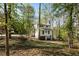 Two-story home with white siding nestled on a wooded lot with mature trees and a sloping yard at 131 Cypress St, Roswell, GA 30075
