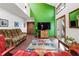 View of the living room features a green accent wall, brick floors, and large windows overlooking the trees at 131 Cypress St, Roswell, GA 30075