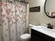 Cozy bathroom featuring floral shower curtain, dark wood vanity, sink, toilet, and vanity mirror at 1380 Cedar Hl, Douglasville, GA 30134