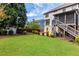 A beautiful backyard features green grass, mature trees, garden, shed, and a deck with staircase at 5081 Stone Moss Way, Hoschton, GA 30548