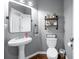 Cozy powder room with a pedestal sink, mirror, and toilet at 5081 Stone Moss Way, Hoschton, GA 30548