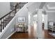 Bright foyer with hardwood floors, staircase with dark railings, and decorative columns leading to other rooms at 5081 Stone Moss Way, Hoschton, GA 30548
