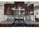 Stylish kitchen with stainless steel appliances, dark cabinets, granite countertops, and tiled backsplash at 1332 Worcester Trl, Mcdonough, GA 30253