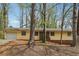 Charming single-story home with a light yellow facade and mature trees surrounding the property at 1360 Cypress Ridge Cir, Stone Mountain, GA 30083