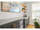 Stylish bar area featuring black cabinets with gold handles, wine fridge, open shelving, and eye-catching artwork at 9893 Colchester St, Douglasville, GA 30135