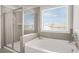 This bathroom features a glass enclosed shower and a soaking tub beneath a window with privacy blinds at 9893 Colchester St, Douglasville, GA 30135