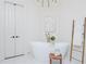 Bright bathroom featuring a white soaking tub, wood stool, wall art, and decorative ladder and towels at 425 Prestwick Ct, Alpharetta, GA 30005