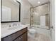 Well-lit bathroom with a glass-enclosed shower over tub, a sleek vanity with modern fixtures, and neutral tile flooring at 13415 Bishops Ct, Roswell, GA 30075