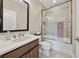 Well-lit bathroom with a glass-enclosed shower over tub, a sleek vanity with modern fixtures, and neutral tile flooring at 13415 Bishops Ct, Roswell, GA 30075