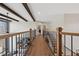 Hallway with hardwood floors, wood railing, black iron spindles, and beamed ceiling at 13415 Bishops Ct, Roswell, GA 30075