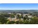 An aerial view showcases a neighborhood surrounded by lush greenery and mature trees under a clear, blue sky at 4025 Bullock Bridge Rd, Loganville, GA 30052