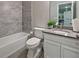 Well-lit bathroom with gray tile, white fixtures, and a green plant on the vanity at 1867 Sterling Chase, Buford, GA 30518