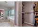 Modern bathroom with a glass shower and tub combination, adjacent to a walk-in closet with storage shelves at 1867 Sterling Chase, Buford, GA 30518