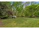 Large grassy backyard featuring mature landscaping, tall trees, and flowering shrubs and ground cover at 3646 Sope Creek Farm Se, Marietta, GA 30067