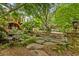 A backyard retreat featuring a stone patio, fire pit, tiered water feature, and lush landscaping with mature trees at 3646 Sope Creek Farm Se, Marietta, GA 30067