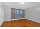 Bedroom with hardwood floors, neutral walls, baseboard trim, and a large window with patterned curtains at 481 Patillo Rd, Stockbridge, GA 30281