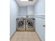 A laundry room with ceramic tile flooring, stainless steel washer and dryer, and pale blue walls at 481 Patillo Rd, Stockbridge, GA 30281