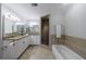Bright bathroom featuring double sinks, granite countertops, walk-in shower, and a separate soaking tub at 432 Ansley Walk Ne Ter, Atlanta, GA 30309