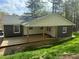 Backyard view of house with a covered porch surrounded by trees and a lawn at 524 S Holly Springs Rd, Woodstock, GA 30188