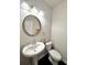 A clean, simple bathroom with a pedestal sink and a round mirror at 3049 Morgan Spring Trl, Buford, GA 30519