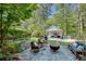 Backyard featuring a stone patio, grill, outdoor seating, and a detached garage in a wooded area at 4000 N Stratford Ne Rd, Atlanta, GA 30342
