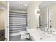 Well-lit bathroom featuring a pedestal sink, tile flooring, and a shower with a gray and white striped curtain at 1100 Howell Mill Nw Rd # 711, Atlanta, GA 30318