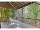 Well-maintained back porch with wood ceiling and railing surrounded by lush trees and greenery at 4880 Stone Moss Path, Hoschton, GA 30548