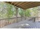 Well-maintained back porch with wood ceiling and railing surrounded by lush trees and greenery at 4880 Stone Moss Path, Hoschton, GA 30548