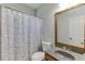 Traditional bathroom featuring a shower with a patterned curtain, a toilet, and a decorative framed mirror at 4880 Stone Moss Path, Hoschton, GA 30548