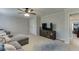 Comfortable living room featuring a plush gray sofa, ceiling fan, and modern entertainment center at 4880 Stone Moss Path, Hoschton, GA 30548