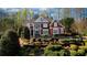Two-story brick home with a front porch and lush landscaping surrounded by mature trees, offering privacy at 4777 Ardmore Ln, Hoschton, GA 30548
