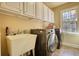 Bright laundry room with washer, dryer, utility sink, and ample storage cabinets at 4777 Ardmore Ln, Hoschton, GA 30548