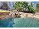 Beautiful pool with a rock waterfall feature and stone surround, creating a backyard oasis for relaxation at 4777 Ardmore Ln, Hoschton, GA 30548