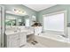 Bright bathroom featuring a large bathtub and double vanity with white cabinets and brushed gold fixtures at 1142 Hidden Spirit Trl, Lawrenceville, GA 30045