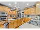 Bright kitchen features light wood cabinets, stainless steel appliances, and pot rack over the island at 1142 Hidden Spirit Trl, Lawrenceville, GA 30045