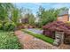 Well-manicured backyard with brick walkway and beautiful shrubs, creating a serene and inviting outdoor space at 53 Paces West Nw Dr, Atlanta, GA 30327