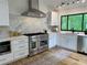 Contemporary kitchen with white cabinetry, marble backsplash, stainless steel appliances and hardwood floors at 541 Earlvine Nw Way, Kennesaw, GA 30152