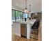 Kitchen island featuring a marble countertop, black stools, and under-counter refrigerator, adjacent to the living area at 541 Earlvine Nw Way, Kennesaw, GA 30152