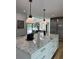 Modern kitchen island with white cabinets, a marble countertop, and pendant lighting, adjacent to the living area at 541 Earlvine Nw Way, Kennesaw, GA 30152