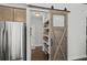 Convenient walk-in pantry with custom shelves and stylish barn door, next to stainless steel refrigerator at 139 Stargaze Rdg, Canton, GA 30114
