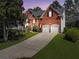 Charming two-story brick home with a well-manicured lawn and a two-car garage at dusk at 1665 Millhouse Lndg, Marietta, GA 30066