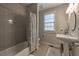 This bathroom features a tub with a shower, a pedestal sink, and a window, providing natural light at 1956 Grace Arbor Ne Ct, Atlanta, GA 30329