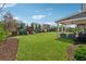 Spacious backyard with lush green lawn, mature trees, and a charming covered patio area perfect for entertaining at 214 Leland Way, Woodstock, GA 30188
