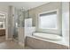 Luxurious bathroom featuring a soaking tub, a separate glass shower, and tiled walls at 214 Leland Way, Woodstock, GA 30188